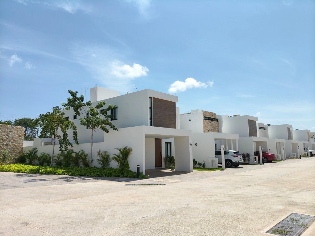 Residencia de Adara con fachada blanca, acento de piedra natural y acceso techado